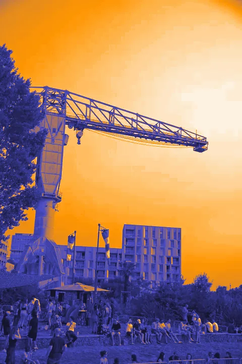 Le public installé au pied de la grue jaune de l’île de Nantes, sous des manches à air, au coucher du soleil.
